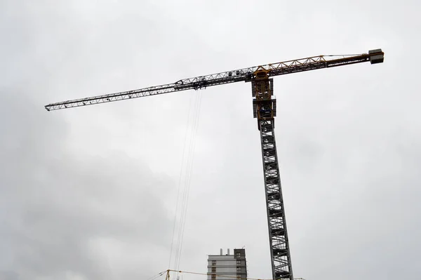 Gran grúa industrial de carga de construcción potente en un sitio de construcción de nuevos edificios y casas contra el cielo —  Fotos de Stock