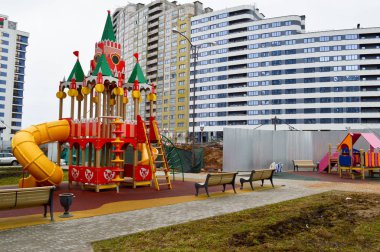 Şehrin yeni bir bölgesinde, yeni bir binanın avlusunda, spor aletleri ve oyuncaklarla açık havada yeni ve modern bir açık hava oyun alanı.