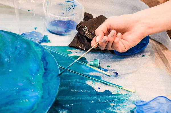 The process of creating a home-made trendy abstract modern pattern painted with a brush of acrylic blue multi-colored resin on a round wooden board — Stock Photo, Image