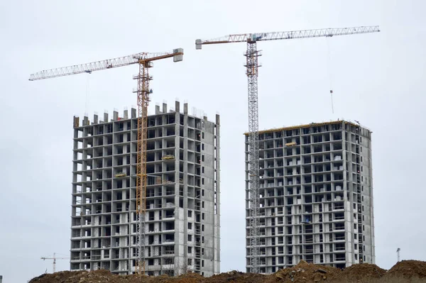 Construction of large modern monolithic frame houses, buildings using industrial construction equipment and large high cranes. Construction of the building in the new micro district of the city