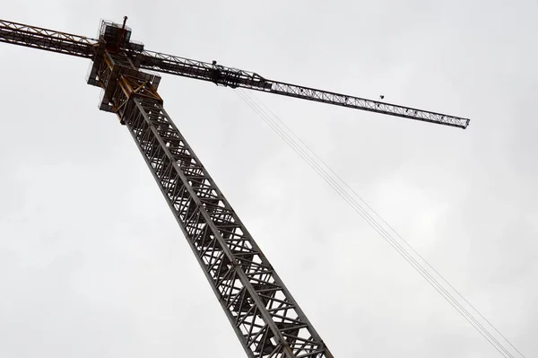 Großer leistungsfähiger Baukran auf einer Baustelle von Neubauten und Häusern gegen den Himmel — Stockfoto