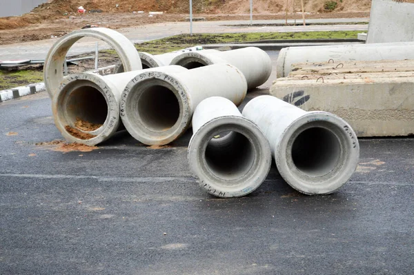 Large concrete stone cement sewer plumbing pipes of large diameter for the industrial construction of water supply or sewage at a construction site during the repair — Stock Photo, Image