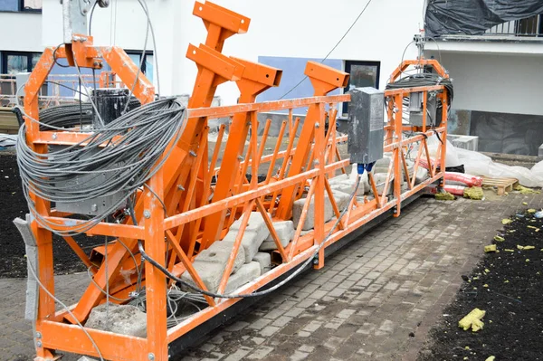 Grote ijzeren metalen gevel lift wieg voor het heffen van werknemers en een lading bouwmaterialen tijdens de reparatie van de buitengevel en het schilderen van het gebouw — Stockfoto