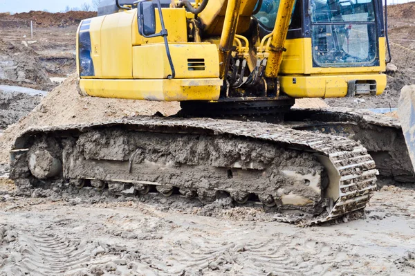 Grote heldere gele krachtige industriële zware graafmachine trekker, bulldozer, gespecialiseerde bouwmachines voor wegreparatie tijdens de bouw van een nieuw micro-district in een grote stad — Stockfoto