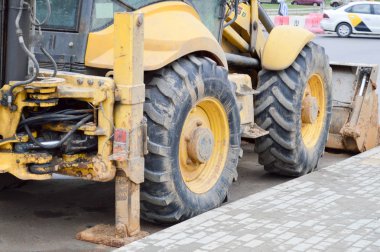 Büyük, sarı, güçlü endüstriyel kazıcı traktör, buldozer, büyük bir şehirde yeni bir mikro bölge inşaatı sırasında yol onarımı için özel inşaat ekipmanları.