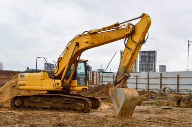 Büyük, sarı, güçlü endüstriyel kazıcı traktör, buldozer, büyük bir şehirde yeni bir mikro bölge inşaatı sırasında yol onarımı için özel inşaat ekipmanları.
