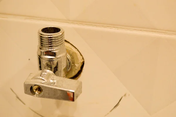 Metallic iron shiny chrome plumbing fittings with thread and valve in the wall of ceramic tiles — 스톡 사진
