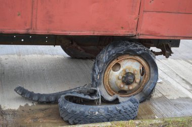 Büyük siyah paslı lastik. Yırtılmış, eskimiş. Lastiklerle dolu.