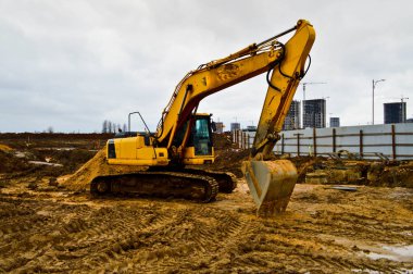 Büyük, sarı, güçlü endüstriyel kazıcı traktör, buldozer, büyük bir şehirde yeni bir mikro bölge inşaatı sırasında yol onarımı için özel inşaat ekipmanları.