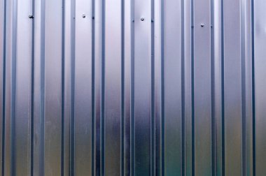 Metal bir levhanın metal profilinden dikey ve çapraz çizgileri olan gümüş teneke bir duvar. Doku, arkaplan