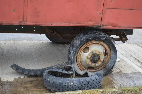 Uma grande roda de borracha enferrujada preta com um rasgado desgastado velho mau cheio de pneus pneu inseguro — Fotografia de Stock