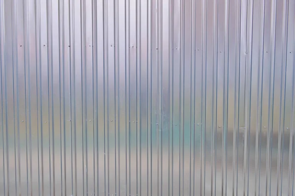 Серебряная железная стена с вертикальными и диагональными полосами из металлического профиля металлического листа. Текстура, фон — стоковое фото