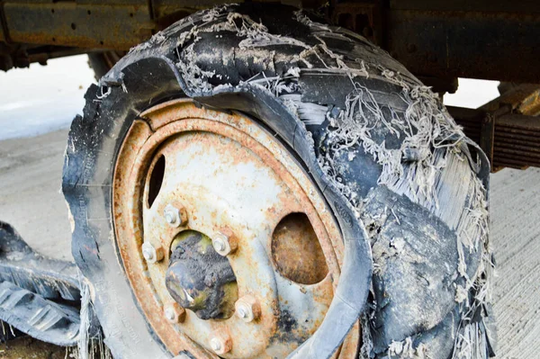 Uma grande roda de borracha enferrujada preta com um rasgado desgastado velho mau cheio de pneus pneu inseguro — Fotografia de Stock