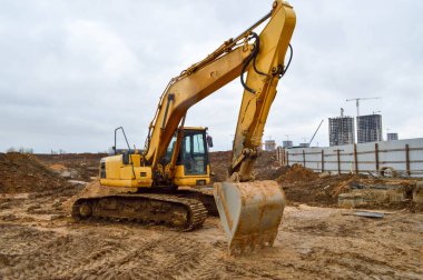 Büyük, sarı, güçlü endüstriyel kazıcı traktör, buldozer, büyük bir şehirde yeni bir mikro bölge inşaatı sırasında yol onarımı için özel inşaat ekipmanları.