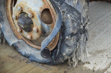 Büyük siyah paslı lastik. Yırtılmış, eskimiş. Lastiklerle dolu.