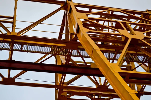 Çağdaş bir inşaat şantiyesinde kargo taşımak için desteklere bağlı durağan, ağır, sarı, demir ağırlıklı, sanayi tipi, güçlü, köprü tipi vinç. — Stok fotoğraf