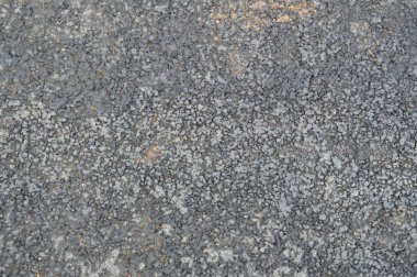 Küçük çakıl taşları ve çatlakları olan gri asfalt yol. Doku, arkaplan