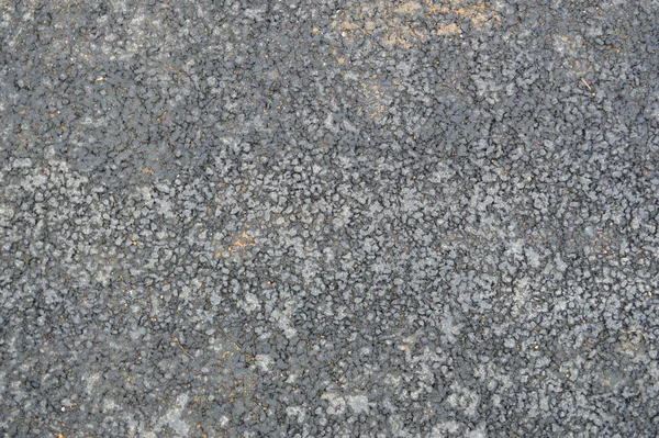 灰蒙蒙的沥青路面上有小卵石和裂缝。结构、背景 — 图库照片