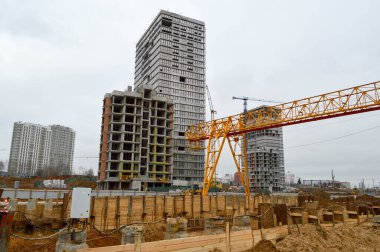 Çağdaş bir inşaat şantiyesinde kargo taşımak için desteklere bağlı durağan, ağır, sarı, demir ağırlıklı, sanayi tipi, güçlü, köprü tipi vinç.