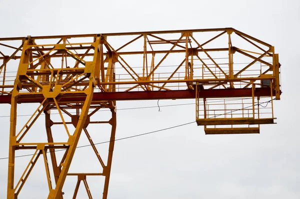 Hög tung gul metall järn bärande konstruktion stationär industriell kraftfull portalkran av brotyp på stöd för att lyfta last på en modern byggarbetsplats av byggnader och hus — Stockfoto