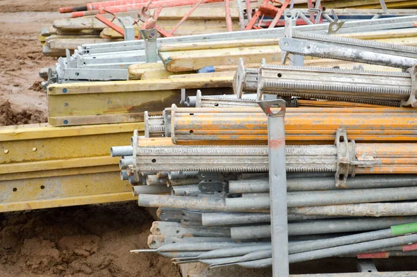 Um monte de materiais de construção com peças sobressalentes de metal, varas, vigas, tubos em um armazém de canteiro de obras ao ar livre — Fotografia de Stock