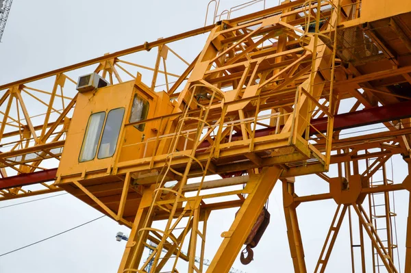 Hög tung gul metall järn bärande konstruktion stationär industriell kraftfull portalkran av brotyp på stöd för att lyfta last på en modern byggarbetsplats av byggnader och hus — Stockfoto