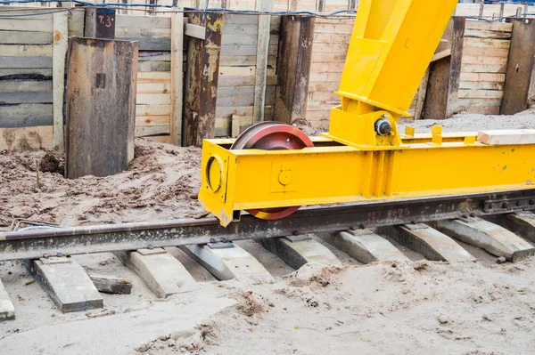 Grote ijzeren metalen gele steunen op rails met wielen met inductiemotor van een grote stationaire industriële krachtige portaalkraan van het brugtype — Stockfoto