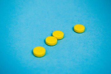 Hastalıkların tedavisi ve mavi arka planda Coronavirus için ilaç ve virüs ilaçlarının ve vitaminlerin öldürülmesi için sarı yuvarlak tıbbi ilaçlar