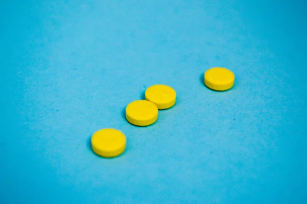 Желтый круглый медицинский препарат для лечения заболеваний и уничтожения микробов и вирусов таблетки и витамины лекарства от коронавируса на голубом фоне — стоковое фото
