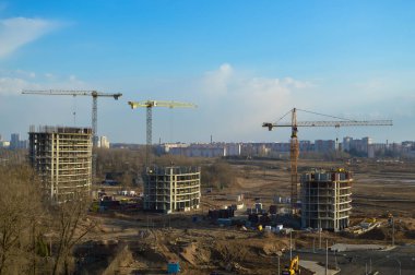 Vinçleri ve binaları olan büyük bir inşaat alanının üst manzarası metropolün büyük şehrinin beton monolitik çerçeve paneli çok katlı gökdelenleri