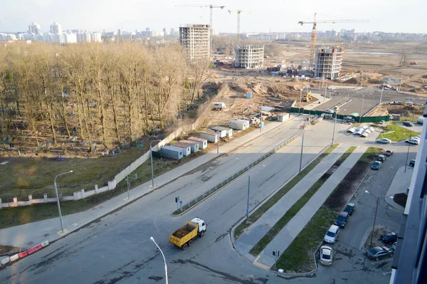 A large dump truck rides to a construction site and carries sand along an asphalt road. View from above