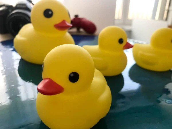 Linda banheira de borracha amarela brinquedo patos nadar em um fundo de água azul — Fotografia de Stock