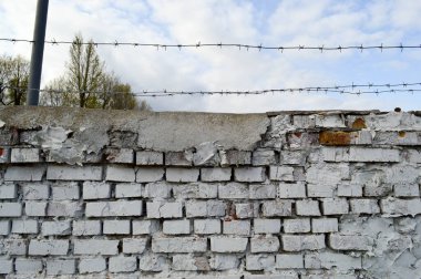 Güzel, beyaz, boyanmış, eski püskü bir duvar. Çatı katında çatlaklar, dikişler ve mavi gökyüzüne dikenli teller var. Doku, arkaplan