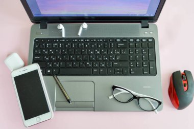 Evde iş yeri, bilgisayarlı cep telefonu akıllı cep telefonu kalem kulaklık ve pembe arka planda gözlük ile uzaktan çalışma merkezi.