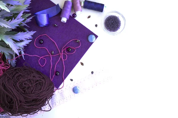 Materials for needlework in violet color on a white background.