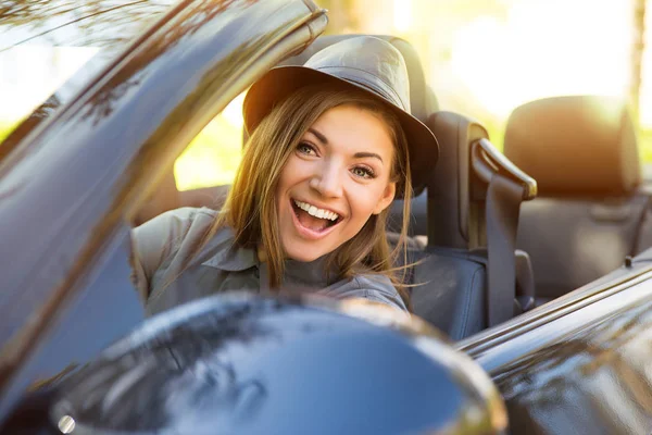 Shot of a young cute woman enjoying a drive in a convertible loving the breeze in her face — Stock Photo, Image