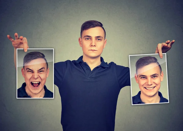 Hombre serio sosteniendo dos máscaras de emoción diferente cara de sí mismo — Foto de Stock