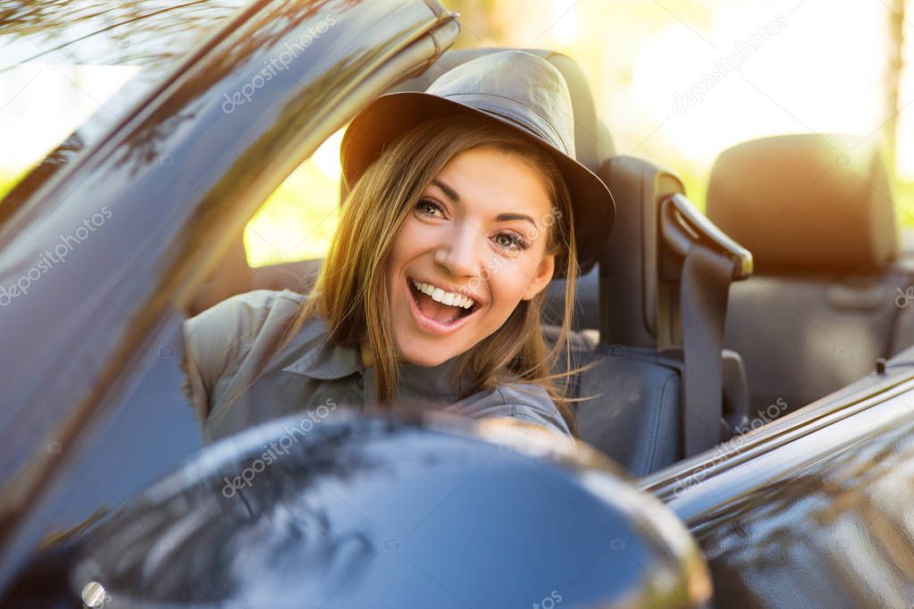 Shot of a young cute woman enjoying a drive in a convertible loving the breeze in her face