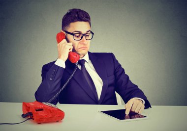 Ciddi telefon sohbet ve tablet bilgisayar kullanarak iş adamı 