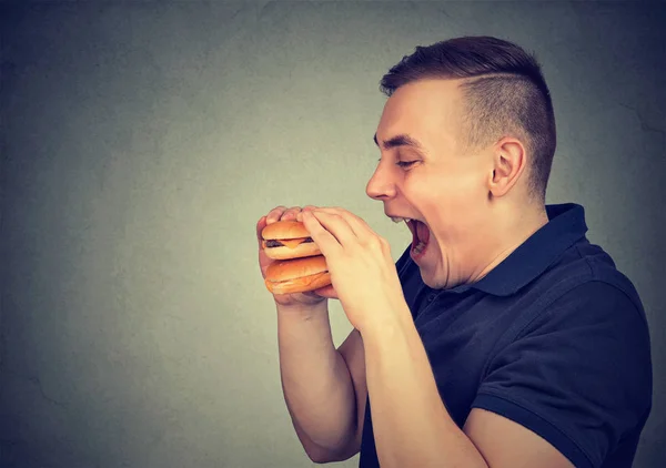 Člověk jíst nezdravé jídlo dvojitý cheeseburger — Stock fotografie