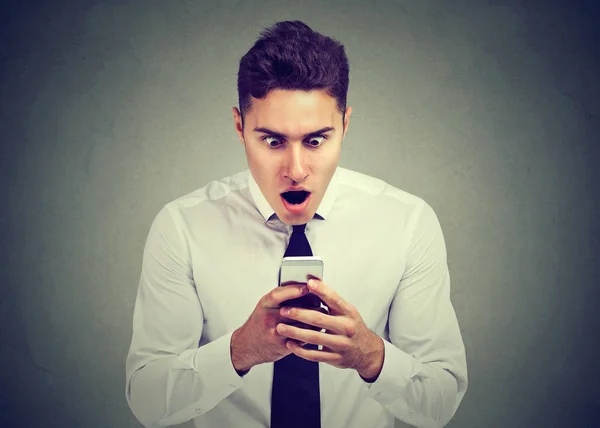 Überraschter Mann schaut aufs Telefon und sieht unerwartete Nachrichten oder Fotos mit erstaunter Emotion im Gesicht — Stockfoto