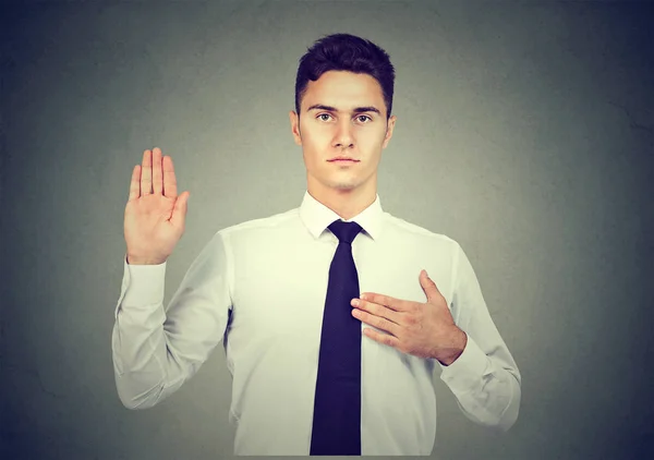 Handsome young business man making an oath promise on gray background — Stock Photo, Image