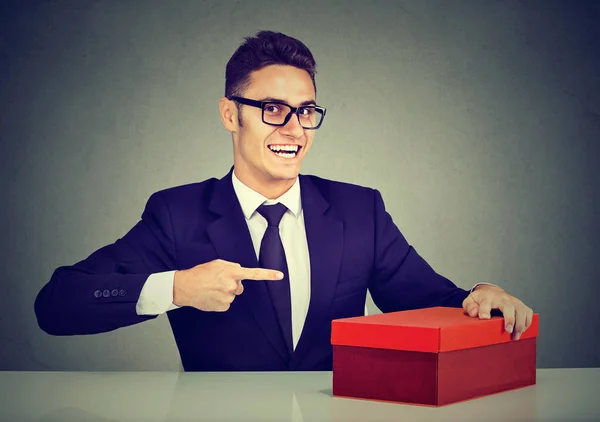 Vendedor sonriente joven hombre de negocios anunciando su producto en caja roja — Foto de Stock