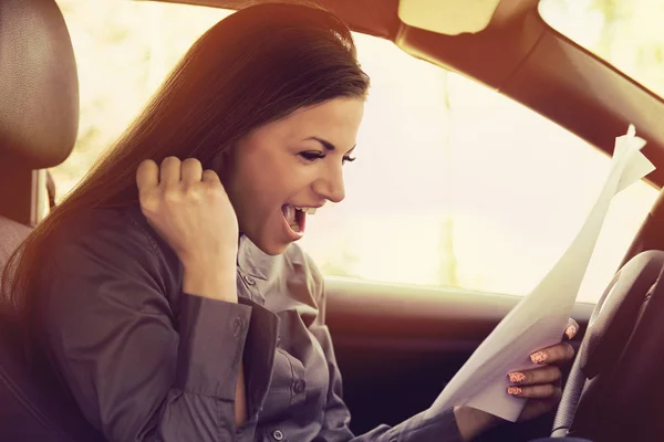 Joven mujer emocionada dentro de nuevos documentos de lectura de coches — Foto de Stock