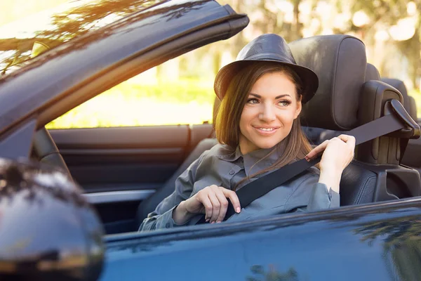 Young woman pulling on seat belt inside black car. Life-saving measures — Stock Photo, Image