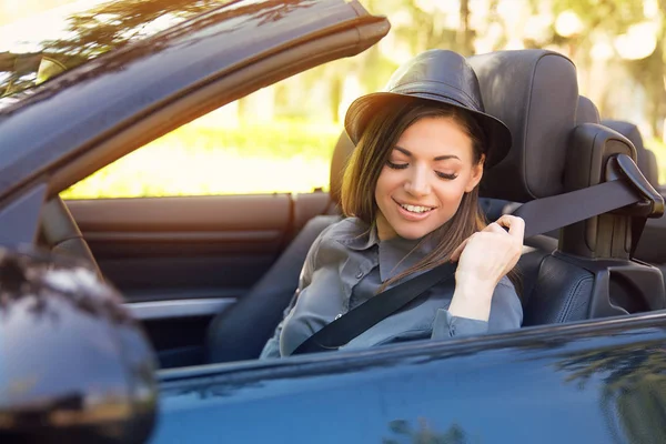 Young woman pulling on seat belt inside black car. Life-saving measures — Stock Photo, Image