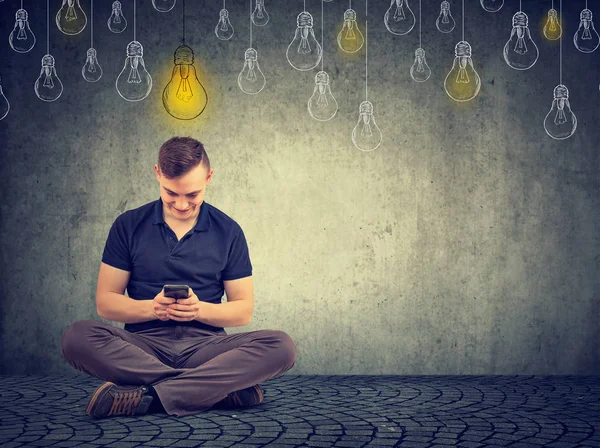 Başının üstünde parlak ampul ile akıllı telefon kullanan adam 