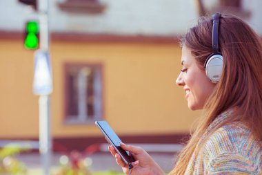 Yeşil ışık geçiş street yürüyüş cep telefonuna müzik dinlerken kulaklık ile mutlu kadın 