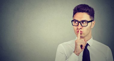 Secret guy. Man saying hush be quiet with finger on lips gesture looking to the side  clipart