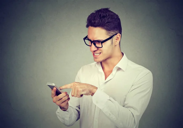 Joven frustrado enviando mensaje de texto usando teléfono móvil — Foto de Stock